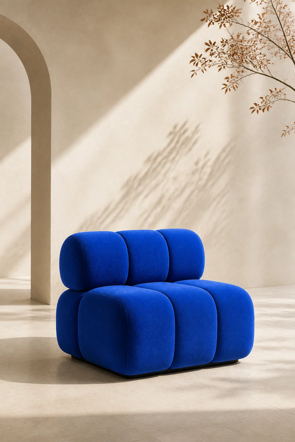Cobalt-blue chair in a bright cream interior with an arch and diagonal sunlight.