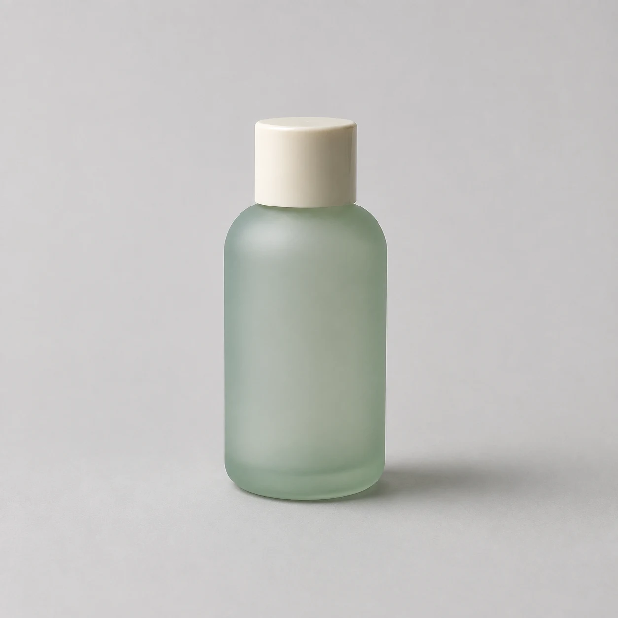 Illustrative reference photo of a frosted sage-green bottle with an ivory cap on a neutral background